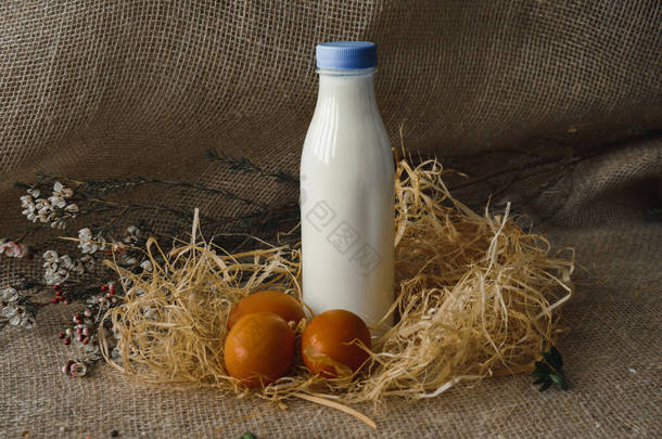 一瓶牛奶和鸡蛋。粗麻布背景上的乡村风格
