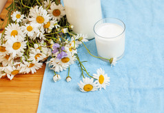 简单时尚的木制厨房，桌上放着一瓶牛奶和玻璃，夏天的鲜花，甘菊，希尔特