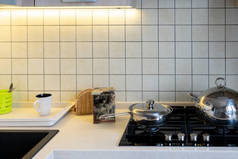 一个明亮厨房的碎片，上面有一个黑色的玻璃陶瓷气罐。煤气炉上有一个铁锅和一个铁锅.