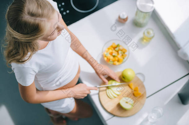 孕妇用刀煮水果沙拉在家里的头顶视图