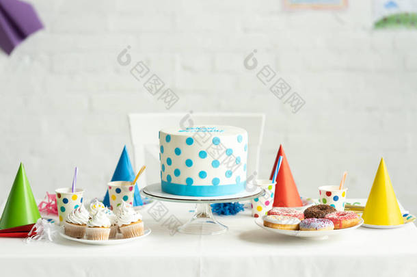 与蛋糕、 甜甜圈和纸杯在节日的餐桌上美味的生日蛋糕