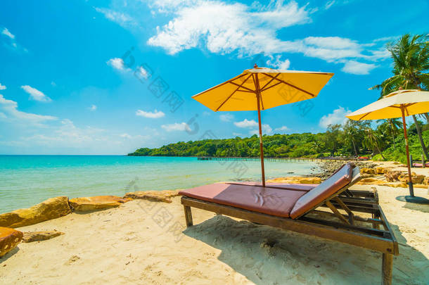 在美丽的<strong>热带海滩</strong>和海洋与椰子棕榈树在天堂岛的旅行和假期的雨伞和椅子