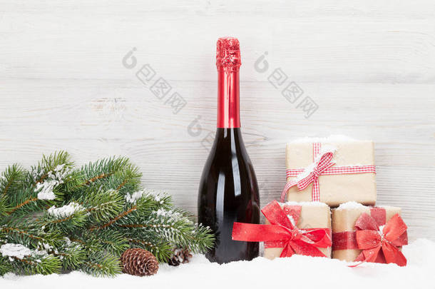 圣诞节礼品盒, 香槟瓶和圣诞节杉木树枝在浅色木背景