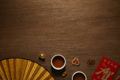 茶杯、扇子、木质表面上的象形文字和金币的顶视图