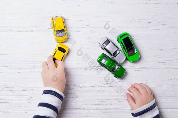 儿童手玩微型玩具车、木制背景、顶视图
