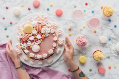 大理石桌上的粉红色生日蛋糕, 糖果, 甜蛋糕和奶昔的纹身手裁剪视图 
