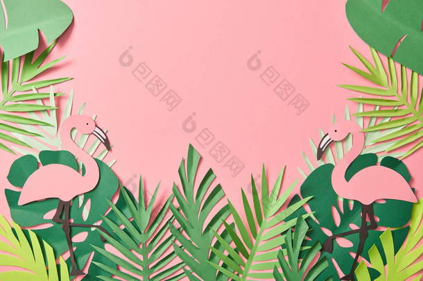 在粉红色背景的绿棕榈叶上<strong>剪纸</strong>火烈鸟的顶视图，带有复制空间