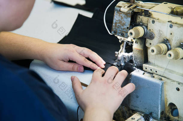 妇女在<strong>缝纫机</strong>上与面料打交道.女裁缝在她的设备后面工作。裁剪工艺、设计工场、服装业概念