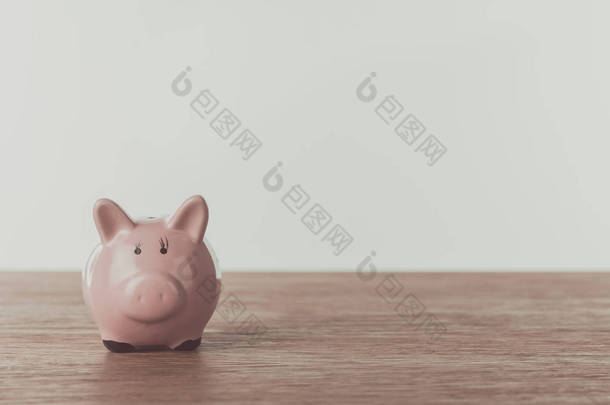 小粉红存钱罐在木桌上, 节省的概念