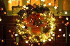 圣诞绿色的花环，门上挂着红色的铃铛。为寒假装饰的房子的入口。圣诞节和新年美国家庭的典型装潢.