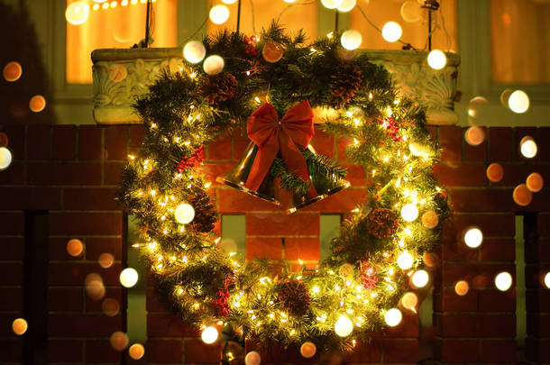 圣诞绿色的花环，门上挂着红色的<strong>铃铛</strong>。为寒假<strong>装饰</strong>的房子的入口。圣诞节和新年美国家庭的典型装潢.
