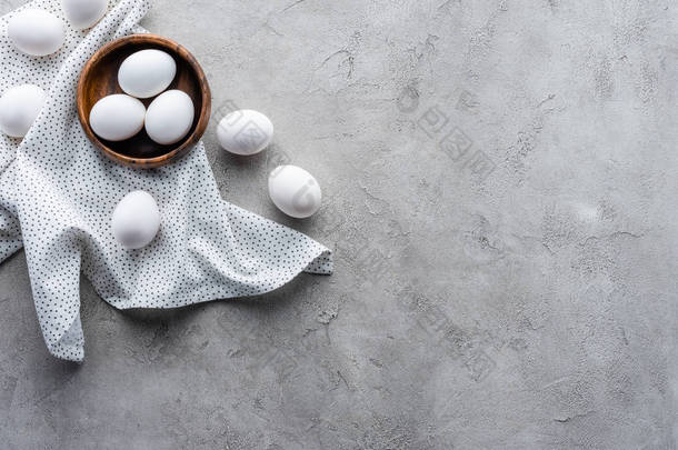 平躺与生鸡蛋在碗和亚麻布在灰色桌上