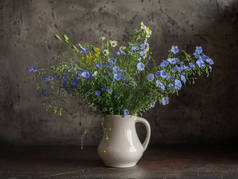 仍然生活与野花。花瓶里的蓝色野花。质朴的台阶.