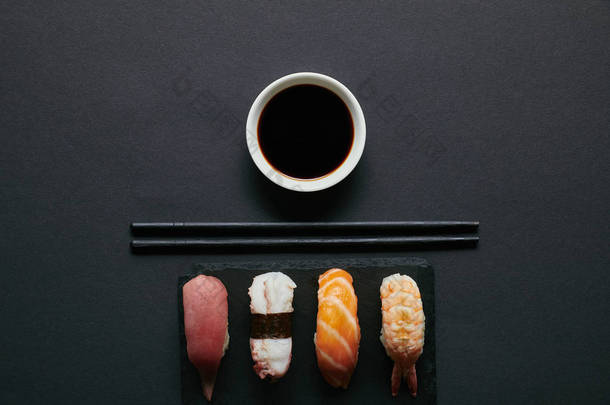 握<strong>寿司</strong>套装, <strong>筷子</strong>和酱油在黑色板上的黑石板上的顶部视图