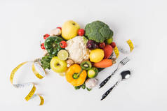 用叉子、勺子和卷尺铺设在白色背景上的蔬菜和水果  