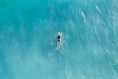 冲浪者在海洋的冲浪板上划桨，可欣赏美景 