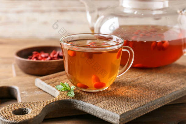 茶壶和杯子里的热茶，<strong>背景</strong>为木制的醋栗果