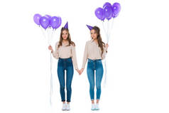 有吸引力的年轻双胞胎与紫罗兰气球手被隔绝在白色