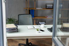 办公室内部有桌子、办公椅和有模糊窗户的架子