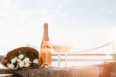 日落时, 在河边的美丽花束、两杯香槟和一瓶香槟酒的特写视图 