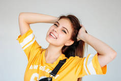 幸福无忧无虑的微笑少女的肖像与黑色长发在灰色背景黄色T恤