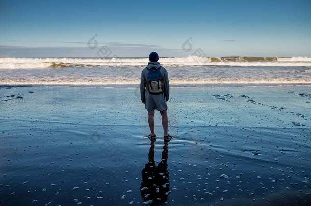 孤独的家伙站在一个被破坏的<strong>大风</strong>沙滩上的街道上, 并考虑海洋