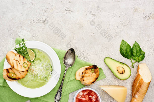 美味奶油绿色蔬菜汤的顶视图,在餐巾纸上用勺子作为餐巾,接近新鲜食材