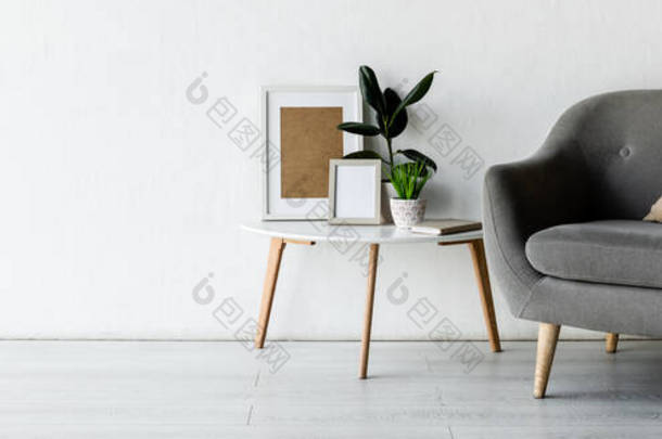 咖啡桌旁舒适扶手椅的全景<strong>定位</strong>- -现代客厅中的绿色植物和框架 