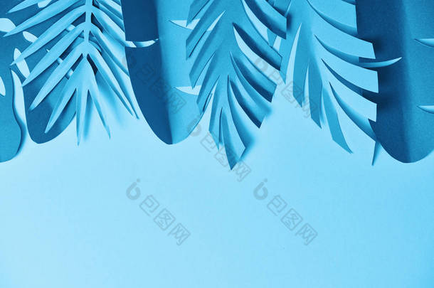蓝色简约剪纸棕榈叶在蓝色背景与复制空间的顶视图