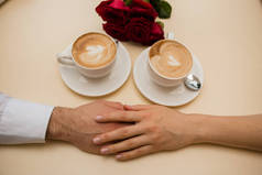 情侣们用咖啡杯在桌上缠住的手