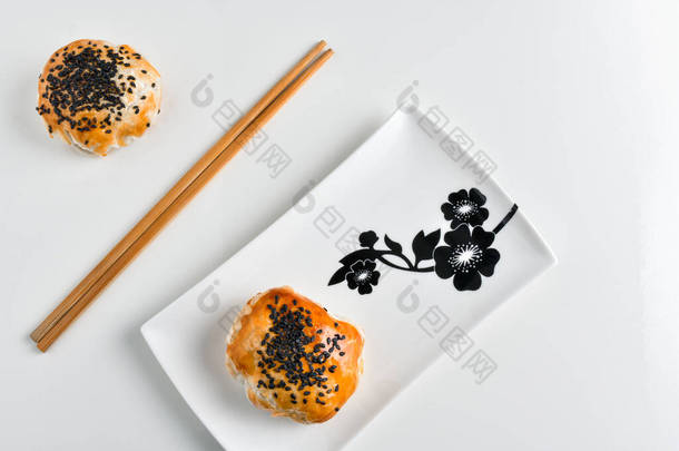 陶瓷盘中的中国红豆酱蛋糕和筷子，白色背景隔离
