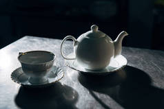 老式茶壶在黑暗的房间金属表面的杯子