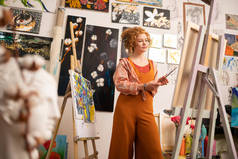 身着橙色服装的艺术家站在画布附近