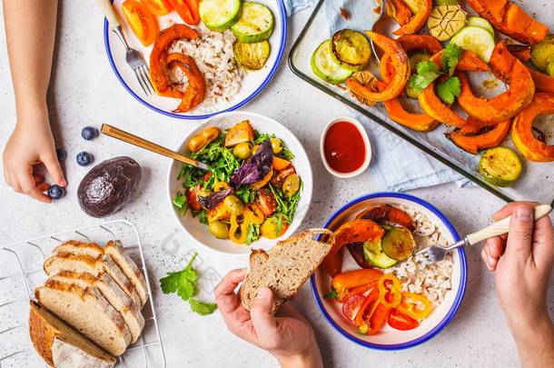 家庭双手<strong>吃</strong>健康食品的平躺。素食主义者午餐桌顶视图。烤蔬菜, 新鲜沙拉, 浆果, 白色背景的面包.