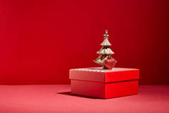 红色礼品盒及红色背景的金黄色装饰圣诞树