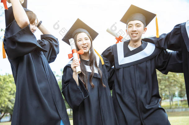 大学校园里穿着毕业礼服拿着毕业证书的快乐<strong>学生</strong>