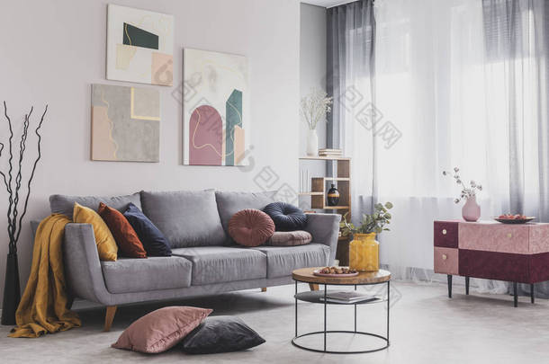 在有大窗户的客厅的灰色沙发上挂在白色<strong>墙</strong>上的抽象画的真实照片