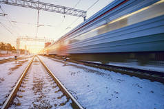 高速列车在冬日落日时分快速通过车站.