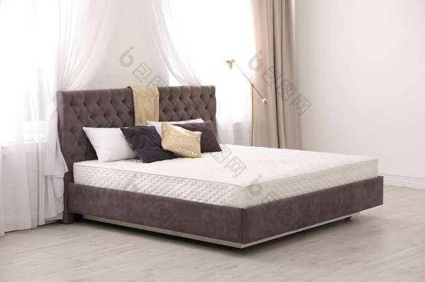 舒适的床, 新床垫靠近窗户在房间里。健康睡眠