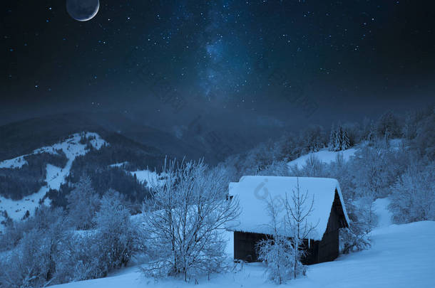 童话般的<strong>星夜</strong>在乌克兰喀尔巴泰山脉与银河银河银河在天空和满月冬季冰霜时间的光芒在一个舒适的小房子的背景下.