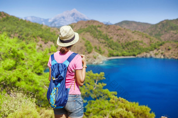 带背包的年轻女子旅行者站在<strong>悬崖</strong>边上, 望着地中海的风景, 夏日度假的概念