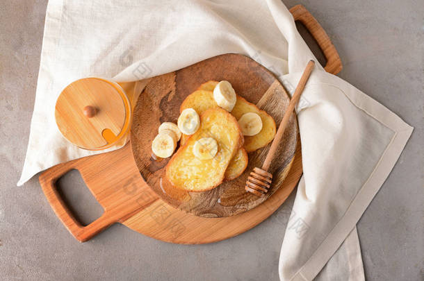 带美味的法国烤面包、蜂蜜和香蕉的灰色背景