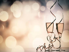 两个香槟眼镜, 带丝带反对节日彩灯和烟花-新年庆典