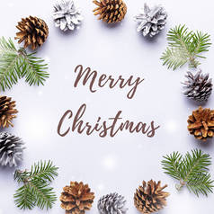 圣诞快乐圆框与杉树树枝，彩绘松果，纸屑在浅灰色背景，复制空间