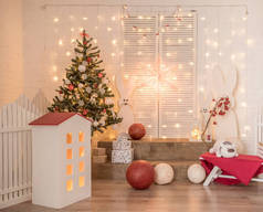 工作室里孩子们的新年装饰。白色的砖墙上有灯光、野兔、树、红球.