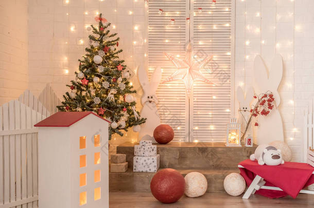 工作室里孩子们的新年装饰。白色的砖墙上有灯光、野兔、树、红球.