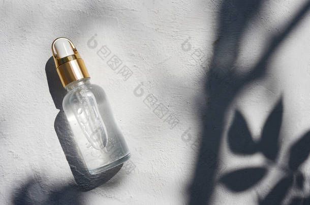 滴水玻璃瓶与化妆品油在纹理混凝土背景阴影。美容美发概念