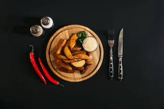 在木木板, 香料, 辣椒和叉子的美味烤土豆在黑色的刀  