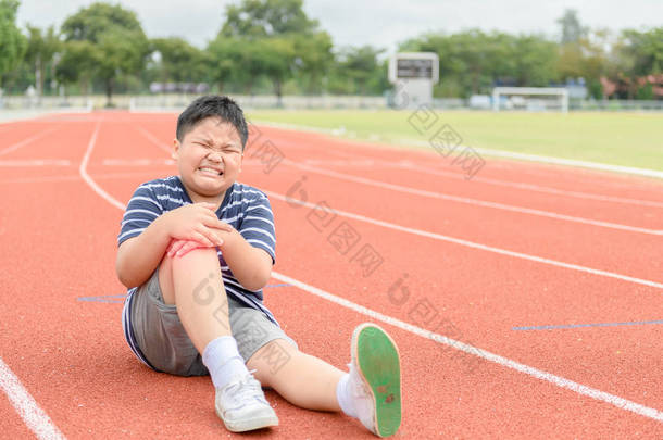 肥胖男孩感到疼痛后, 他的膝盖受伤的轨道上, 运动运动损伤概念