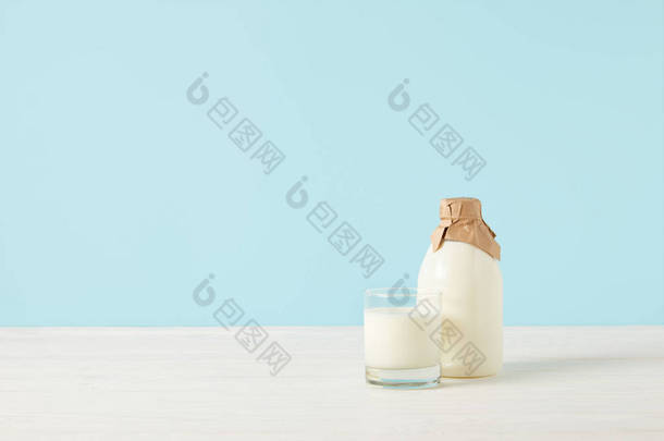 在蓝色背景下用纸包裹的牛奶玻璃和牛奶 